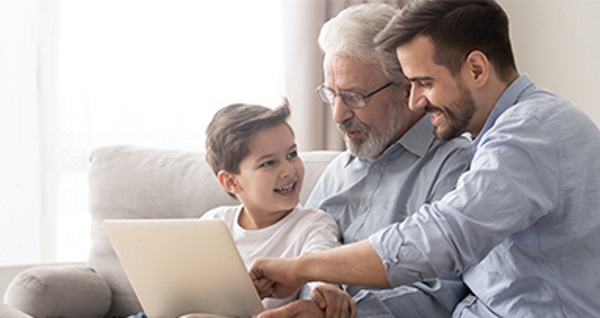 Drei Generationen einer Familie, die gemeinsam auf einen Laptop schauen.