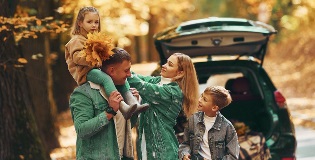 01_Contexte_Saisonnier Familie mit dem Auto im Herbst, die Blätter der Bäume sind gelb