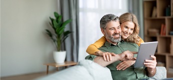 Paar auf einem Sofa beim Betrachten eines Tablets