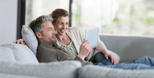 Couple sur un canapé en train de regarder une tablette