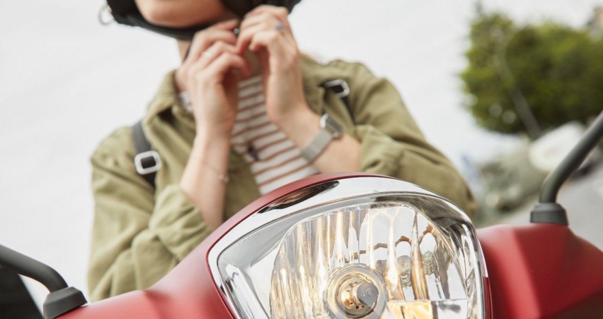 On devine les mains d'une femme sur une moto qui accroche son casque