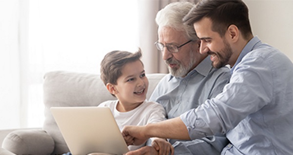 Trois générations de famille regardant ensemble un ordinateur portable.