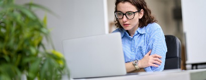 Una persona concentrata sul lavoro davanti a un computer portatile.