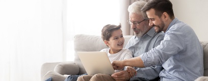 Drei Generationen einer Familie, die gemeinsam auf einen Laptop schauen.
